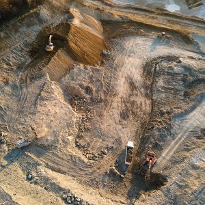 Aerial view of open pit mining site of limestone materials for construction industry with excavators and dump trucks.